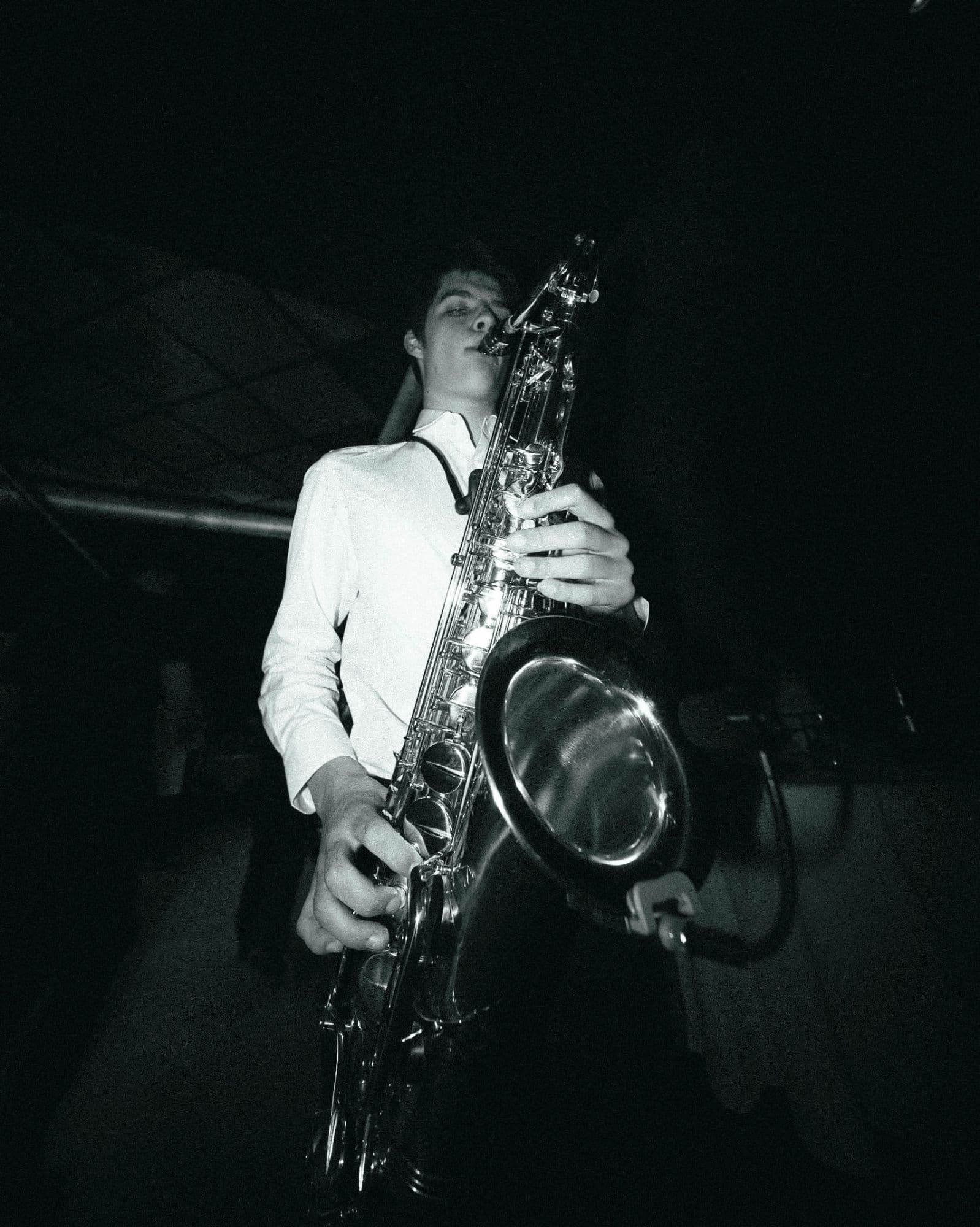 Black-and-white portrait of Louis playing tenor saxophone in a white shirt