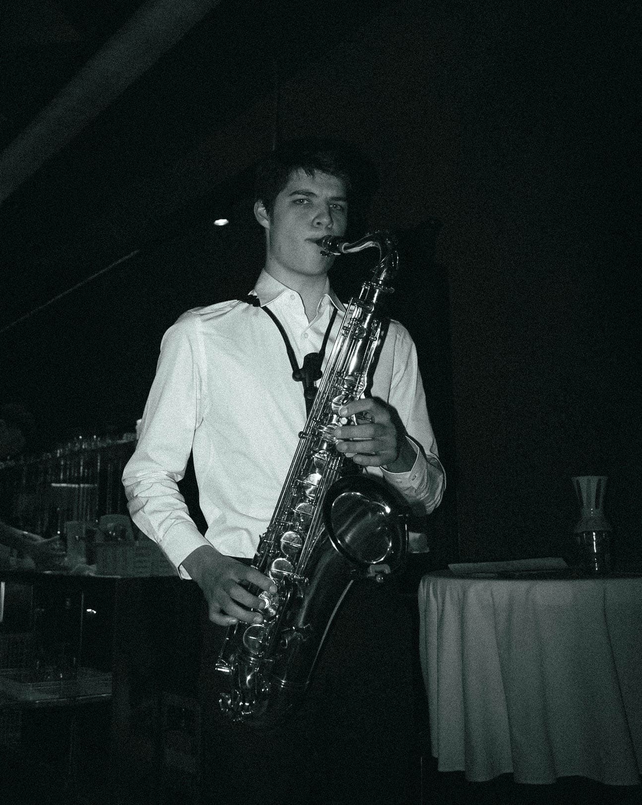 Saxophonist in a white shirt playing tenor saxophone at an evening event
